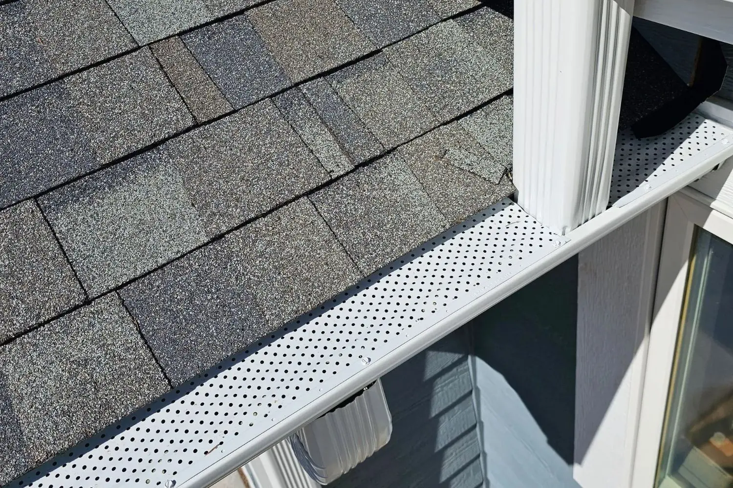 White perforated gutter screen installed along a shingled roof edge in New Prague, MN